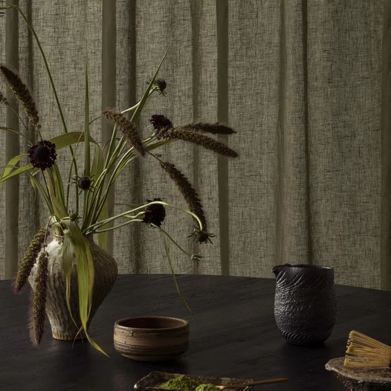 Interior setting featuring table and floral arrangement infront of green drapery