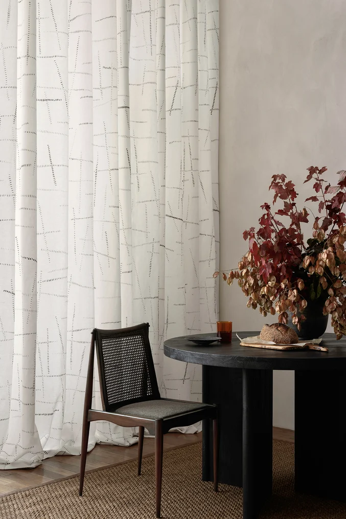 Cream coloured hand block printed drapery with modern wooden furniture and floral arrangement