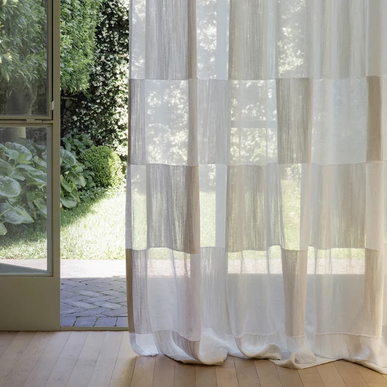 Geometric sheer drapery in doorway to lush green garden